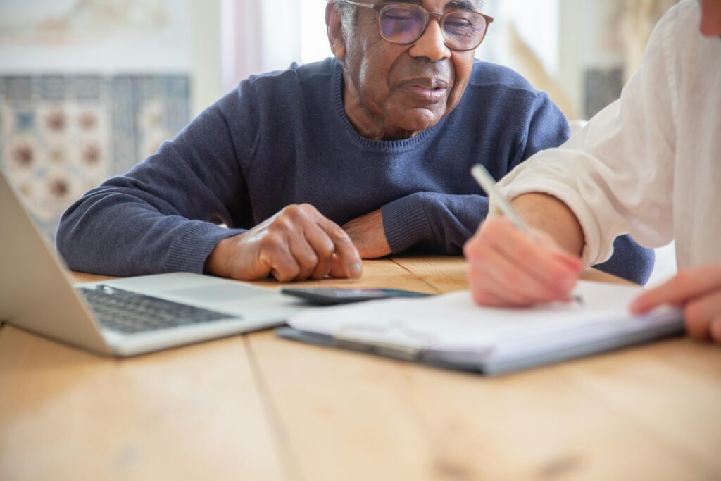 Senior African American man receiving assistance with paperwork at home.